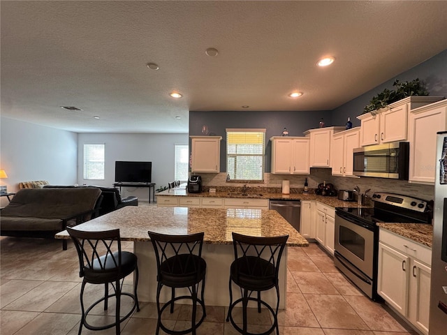 20314 Starfinder Way, Tampa, FL 33647 - kitchen with dark stone countertops, stainless steel appliances, a center island, tasteful backsplash, and a kitchen bar