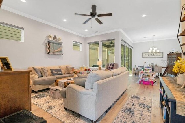 living room featuring crown molding, ceiling fan with notable chandelier, and light hardwood / wood-style flooring