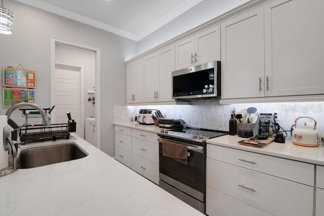 kitchen featuring sink, appliances with stainless steel finishes, white cabinetry, ornamental molding, and decorative light fixtures