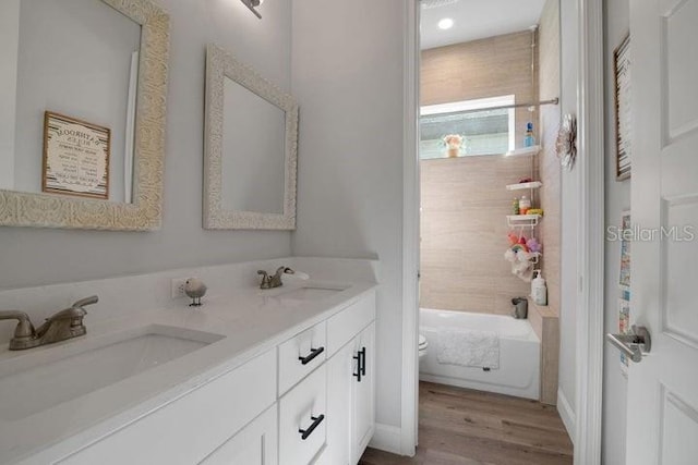 full bathroom featuring hardwood / wood-style flooring, vanity, toilet, and shower / washtub combination