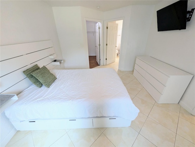 tiled bedroom featuring a spacious closet, ensuite bath, and a closet