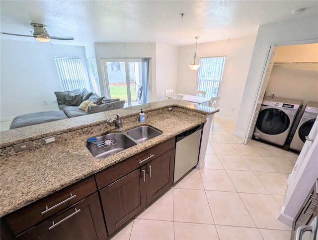 kitchen with sink, decorative light fixtures, washer and dryer, dishwasher, and light stone countertops