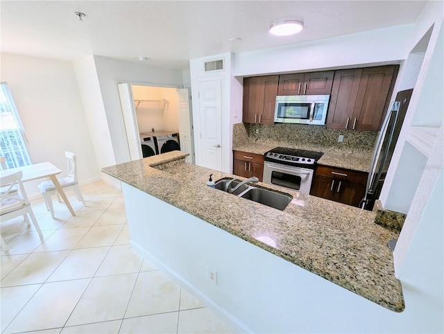 kitchen featuring light stone countertops, appliances with stainless steel finishes, sink, and washing machine and clothes dryer