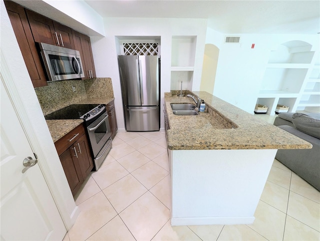 kitchen with built in shelves, sink, light stone counters, light tile patterned floors, and stainless steel appliances