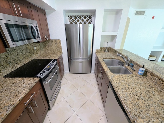 kitchen with light stone counters, appliances with stainless steel finishes, light tile patterned flooring, and sink