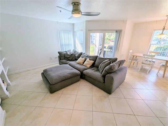 living room with ceiling fan, a textured ceiling, and light tile patterned flooring