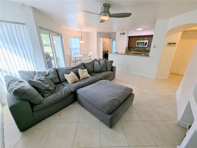 living room with ceiling fan, washer / clothes dryer, and light tile patterned floors