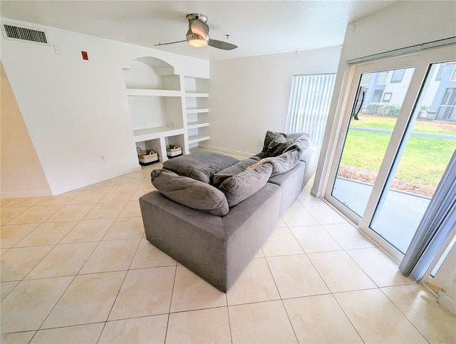 living room featuring light tile patterned floors, ceiling fan, and built in shelves