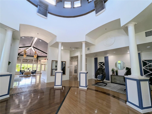 interior space featuring dark hardwood / wood-style flooring, decorative columns, and a high ceiling