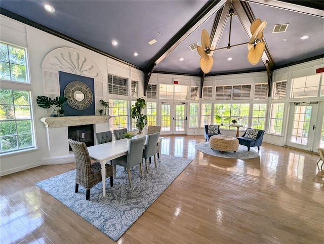 dining space with french doors, a high end fireplace, high vaulted ceiling, and light wood-type flooring