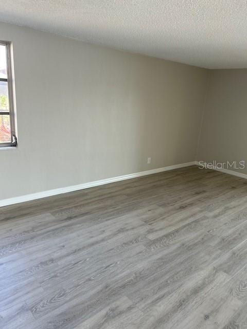 spare room with a textured ceiling and light wood-type flooring