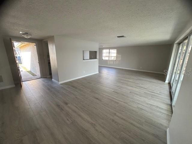 empty room with dark wood-type flooring and a textured ceiling