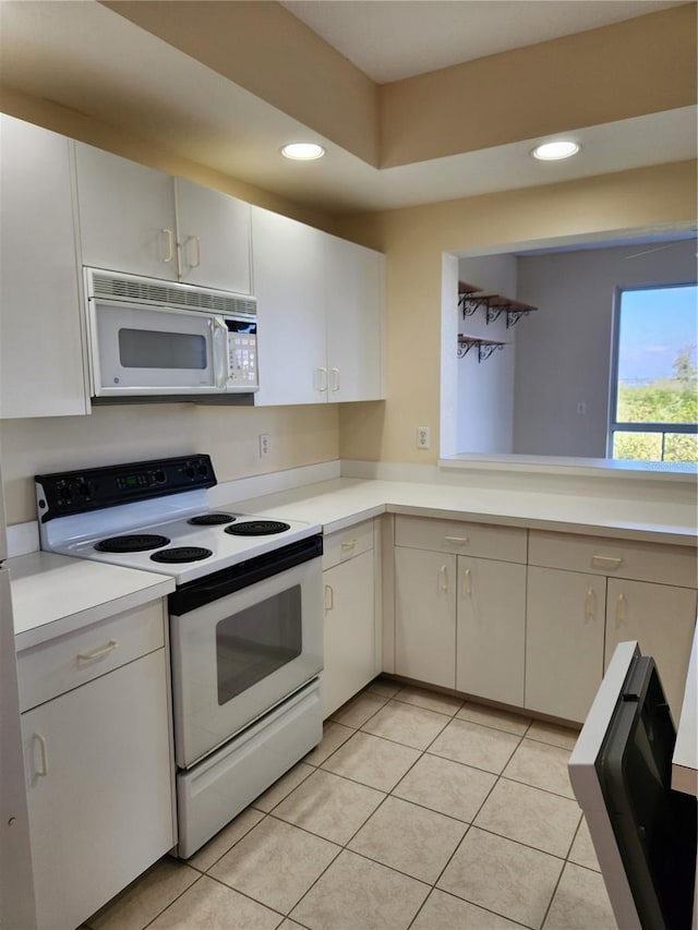 kitchen featuring light tile patterned flooring, white cabinets, and white appliances