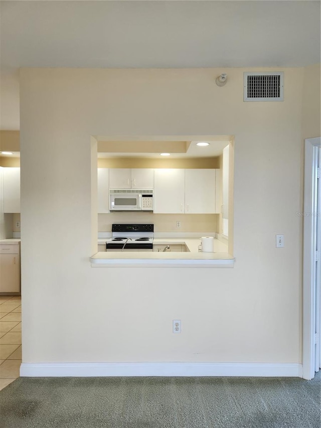 kitchen featuring white appliances, kitchen peninsula, light carpet, and white cabinets