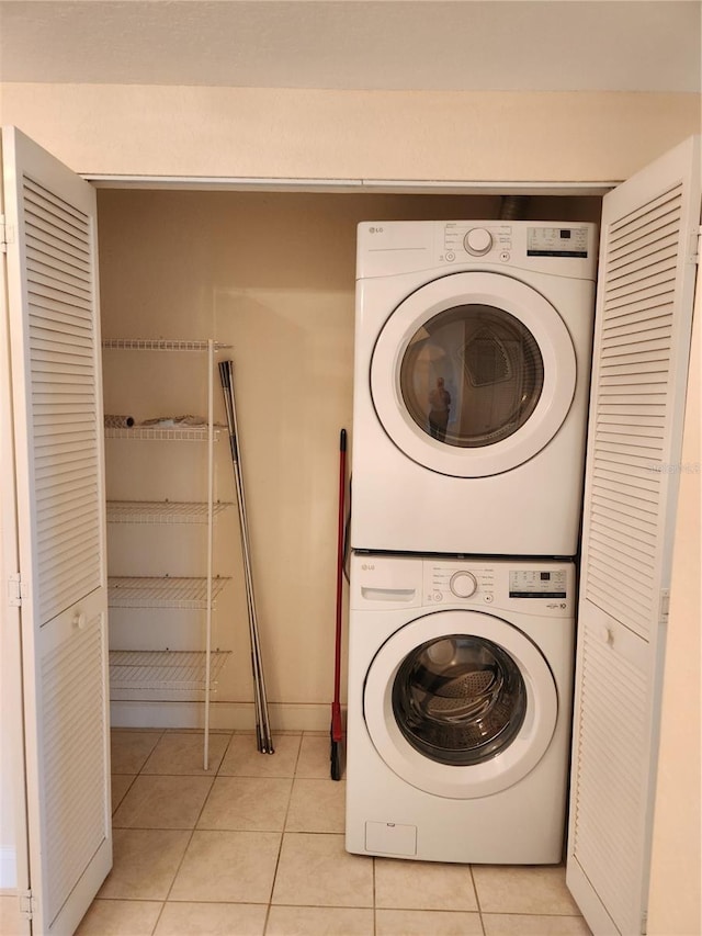 clothes washing area featuring stacked washing maching and dryer and light tile patterned floors