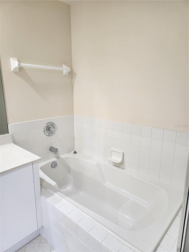 bathroom featuring vanity, tile patterned flooring, and tiled tub