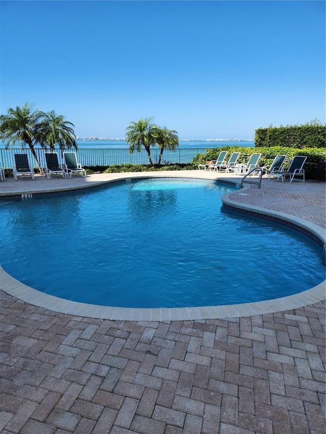 view of swimming pool with a patio and a water view