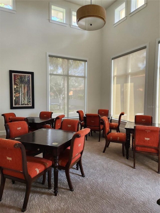 carpeted dining area featuring a towering ceiling