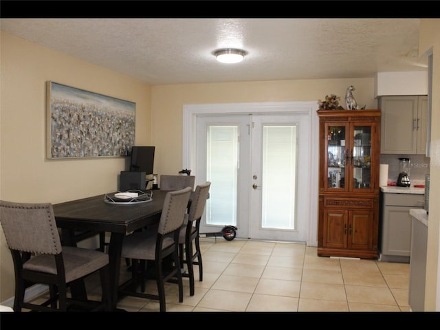 dining room featuring french doors, a textured ceiling, and light tile patterned floors