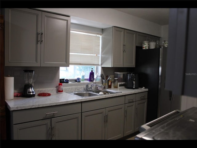 kitchen with gray cabinetry, sink, and range