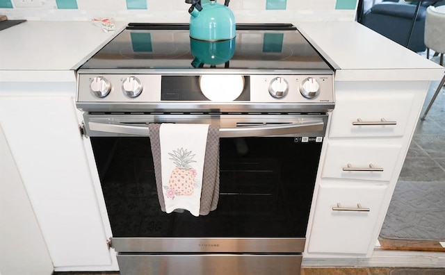 room details with white cabinets and stainless steel electric range