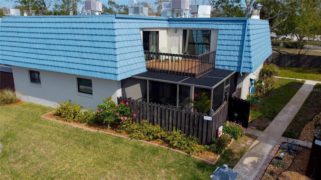 rear view of property featuring a balcony, a yard, and central AC