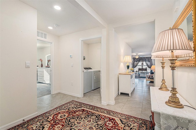 corridor with light tile patterned flooring and separate washer and dryer