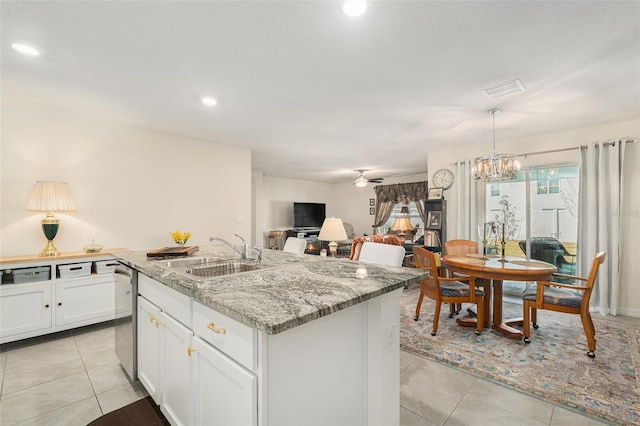 kitchen with sink, light stone countertops, an island with sink, light tile patterned flooring, and stainless steel dishwasher