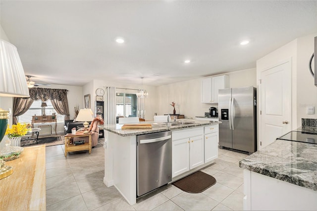 kitchen featuring stainless steel appliances, white cabinetry, a kitchen island with sink, and sink