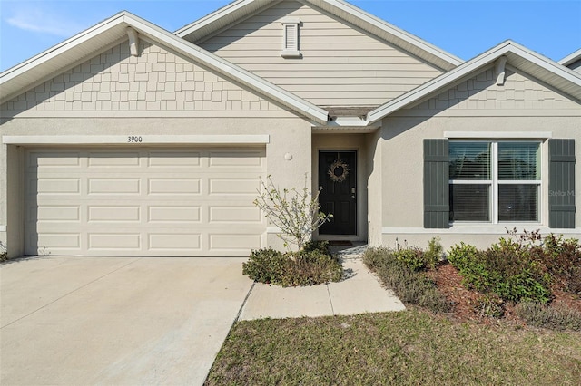 view of front of property featuring driveway, an attached garage, and stucco siding