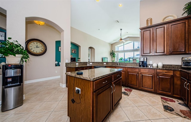 kitchen featuring lofted ceiling, light tile patterned floors, sink, a kitchen island, and dark stone counters