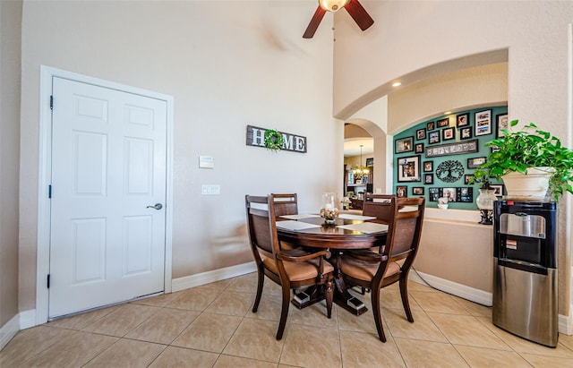 tiled dining area featuring ceiling fan and a towering ceiling