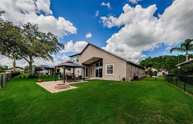 rear view of house featuring a gazebo, a lawn, a patio area, and an outdoor fire pit