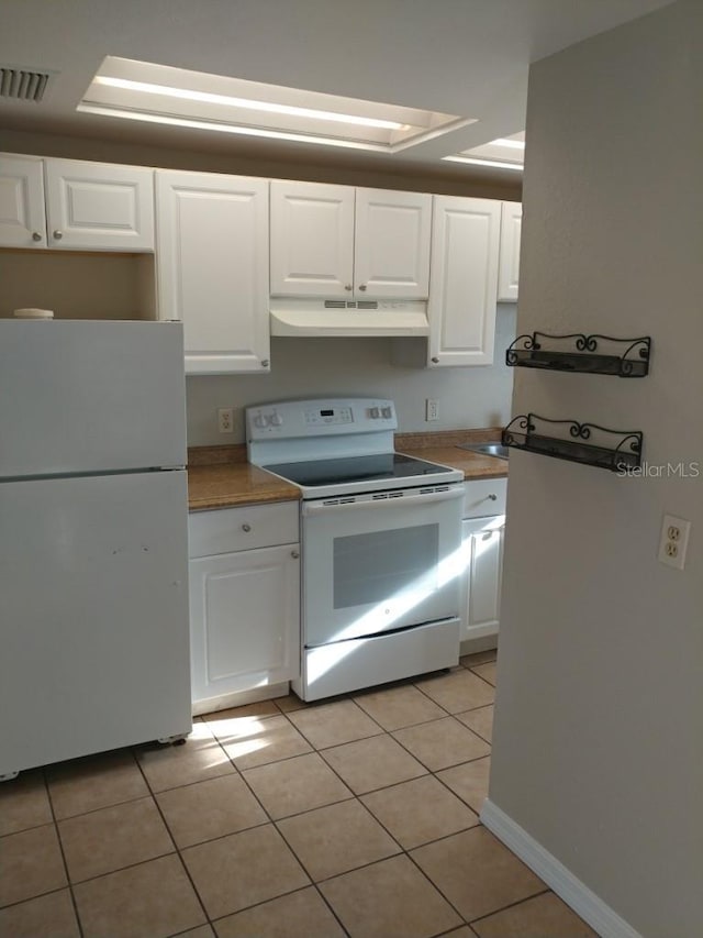 kitchen with white cabinetry, light tile patterned floors, and white appliances