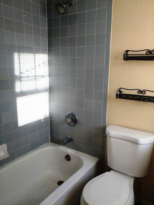 bathroom featuring tiled shower / bath and toilet