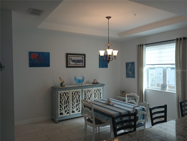 dining space with a chandelier and a raised ceiling