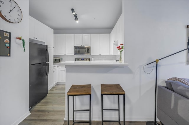4221 W Spruce St Unit 1325, Tampa, FL 33607 - kitchen featuring a breakfast bar, black refrigerator, white cabinets, decorative backsplash, and kitchen peninsula