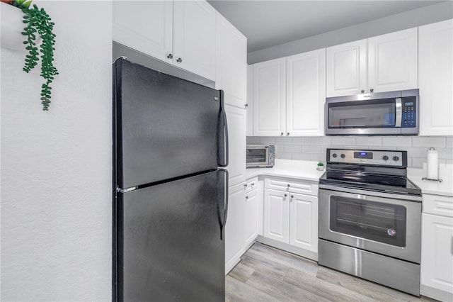 4221 W Spruce St Unit 1325, Tampa, FL 33607 - kitchen featuring appliances with stainless steel finishes, white cabinets, backsplash, and light hardwood / wood-style floors