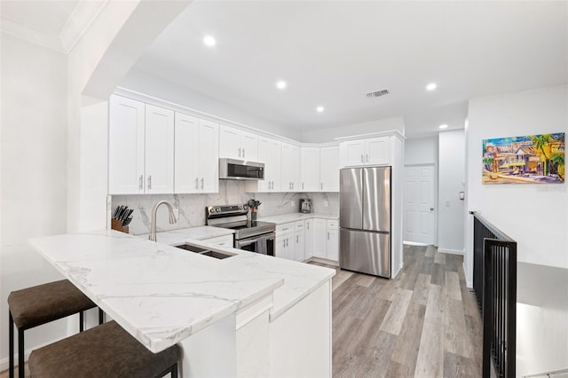 kitchen featuring sink, white cabinets, a kitchen breakfast bar, kitchen peninsula, and stainless steel appliances