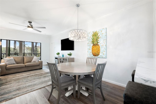 dining area with hardwood / wood-style floors, crown molding, and ceiling fan with notable chandelier