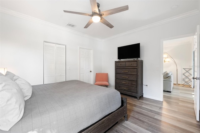 bedroom featuring ceiling fan, ornamental molding, light hardwood / wood-style floors, and a closet