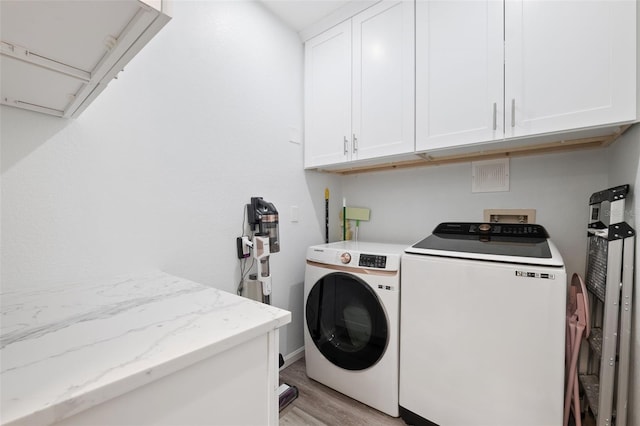 clothes washing area with independent washer and dryer, cabinets, and light hardwood / wood-style flooring