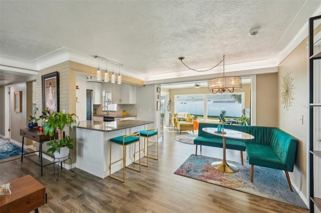 kitchen featuring dark wood-type flooring, white cabinets, dark stone counters, and decorative light fixtures