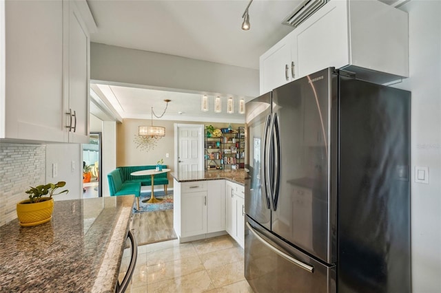 kitchen with white cabinetry, pendant lighting, dark stone countertops, and stainless steel refrigerator