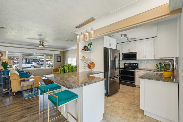 kitchen featuring a kitchen bar, sink, white cabinetry, appliances with stainless steel finishes, and kitchen peninsula