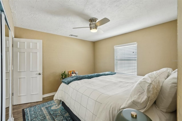 bedroom featuring ceiling fan, hardwood / wood-style flooring, and a textured ceiling