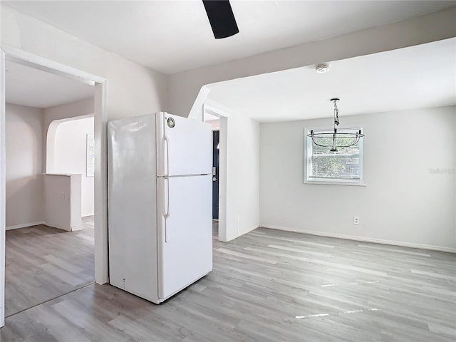 kitchen featuring white fridge, pendant lighting, and light hardwood / wood-style floors