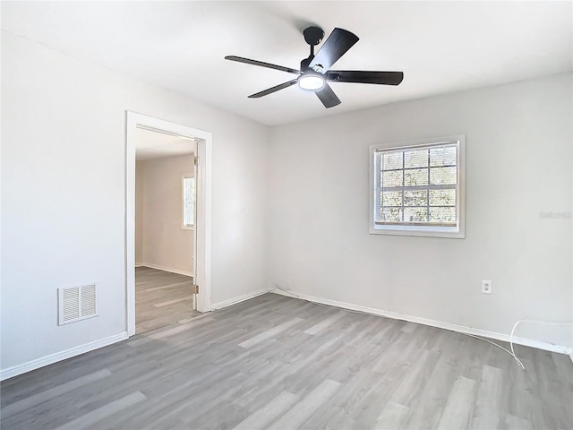 empty room with a wealth of natural light, light hardwood / wood-style floors, and ceiling fan