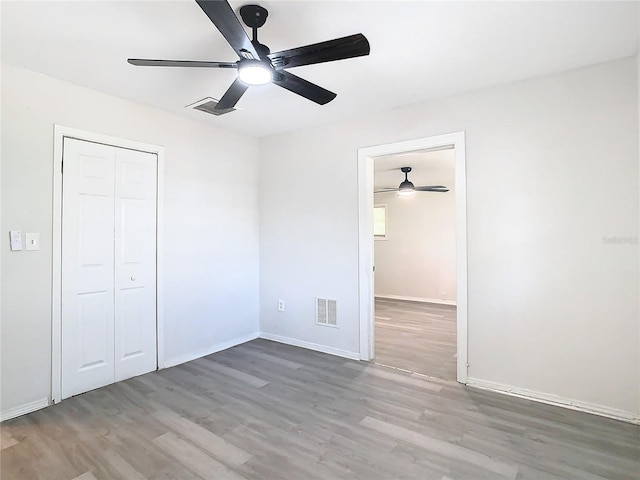 unfurnished bedroom with hardwood / wood-style flooring, ceiling fan, and a closet