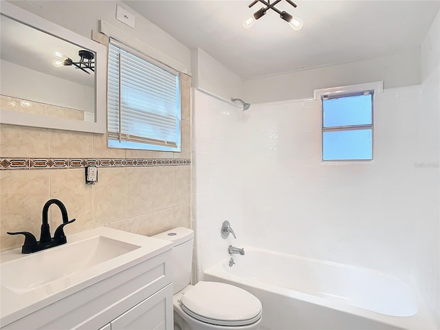 full bathroom featuring tile walls, decorative backsplash, tiled shower / bath combo, vanity, and toilet